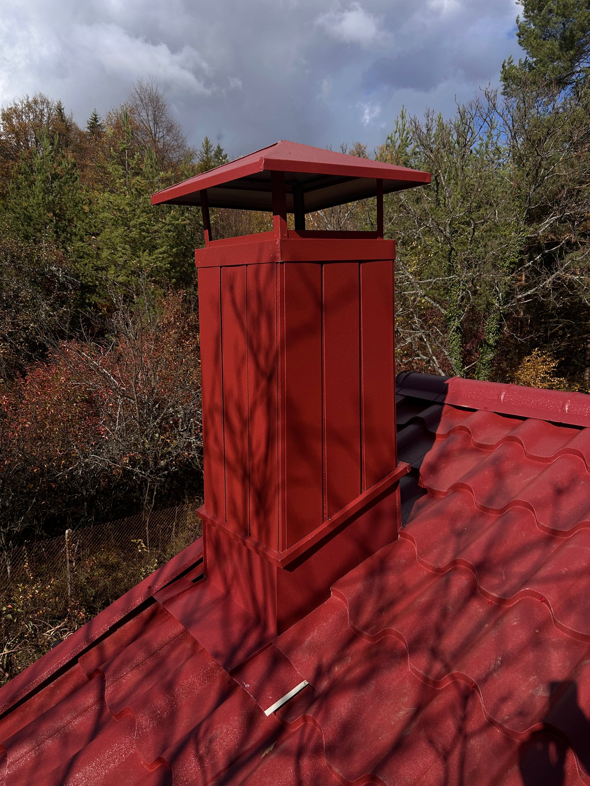 Червен комин на къща сред гориста природа, есенни дървета на заден план за уникален селски пейзаж.